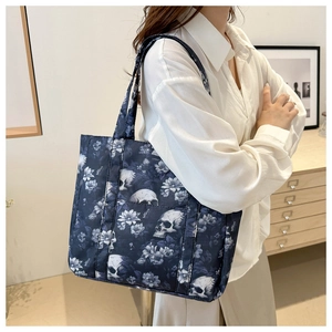 Detail van een grote tote bag met schedelpatroon, versterkte handvatten en vintage bloemen