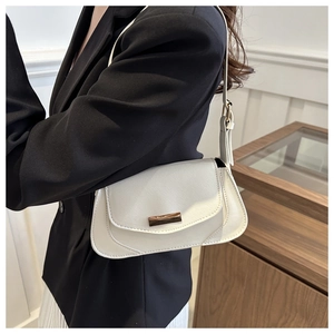 Close-up of minimalist ivory shoulder bag with elegant gold metal buckle detail