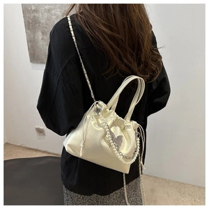 Détail du sac seau en satin blanc avec chaîne en perles et pendentif papillon argenté