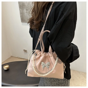 Détail du sac seau en satin rose avec breloque papillon argentée et chaîne perle