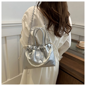 Détail du sac seau argenté avec cordon, papillon métallique et bandoulière en perles