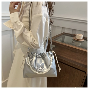 Détail du sac seau argenté à cordon avec chaîne en perles et ornement papillon