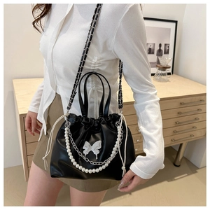 Détail du sac seau noir en PU avec motif papillon et élégantes chaînes de perles