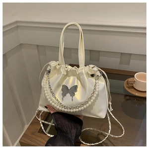 Gros plan du sac seau blanc iridescent avec chaîne de perles et détail papillon