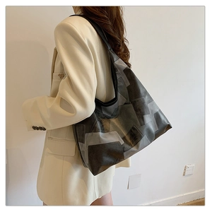 Detail of color-block geometric tote bag on white blazer showing texture and size