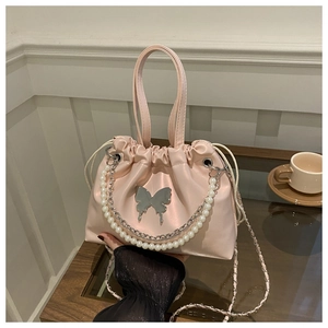 Détail du sac seau en satin rose avec motif papillon et chaîne de perles élégante