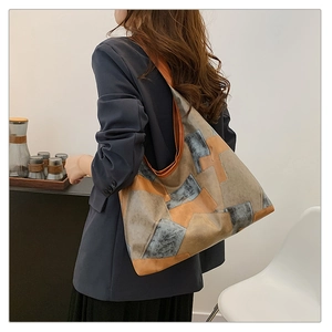 Detailed side view of a large geometric patchwork tote bag on a model's shoulder