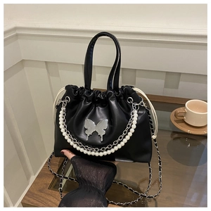 Détail du sac seau noir en PU avec chaîne de perles et breloque papillon argentée