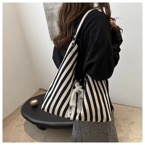 Detail of striped canvas tote with lace bow decoration shown on shoulder