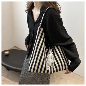 Close-up of black and white striped canvas tote bag with a white lace bow charm detail