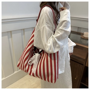 Detail of red and white striped canvas tote bag with a delicate white lace bow accent