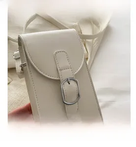 Close-up of minimalist cream PU leather crossbody phone bag with silver metal buckle