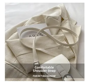 Detailed macro view of the comfortable adjustable leather shoulder strap on a white bag