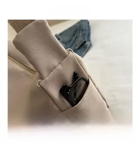 Detail view of the side pocket on beige canvas tote bag with black sunglasses inside