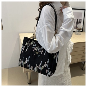 Détail du sac cabas noir avec broderies ondulées colorées et bandoulière dorée