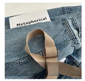 Detail of blue denim fabric with khaki canvas strap and silver metal adjustment buckle