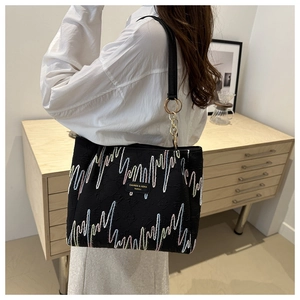 Bolso tote negro minimalista con bordado de olas de colores y anillos metálicos