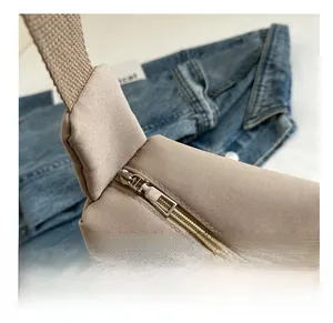 Detail of smooth metal zipper closure and reinforced stitching on beige nylon tote bag