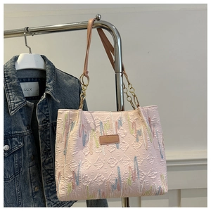 Detail showing pink quilted tote bag with colorful embroidery and metal chain strap
