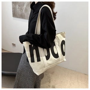 Close-up of cream white tote bag featuring black node text and long shoulder strap
