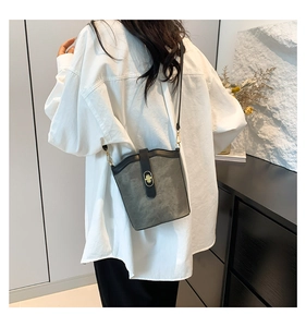 Model view of grey suede bucket bag with black trim and gold twist lock closure