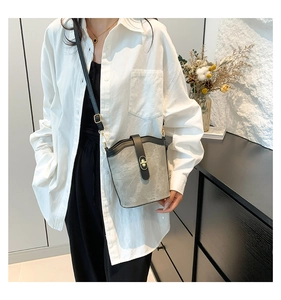 Detail of grey bucket bag with black leather trim and elegant gold twist lock closure