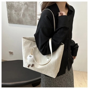 Detail of off-white tote bag featuring unique bamboo wrinkle texture and plush charm