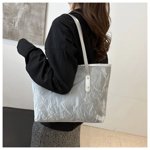Detail of silver metallic tote bag with wrinkled texture and gold rivet accents