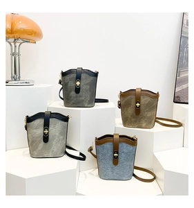 Detail view of four vintage canvas bucket bags with metal locks on tiered stands