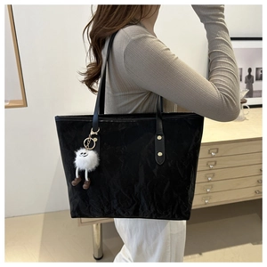 Detailed shot of black tote bag with bamboo wrinkle texture and plush charm accessory