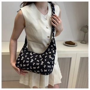 Fashionable hobo bag with bow tie pattern and wide strap shown on a model