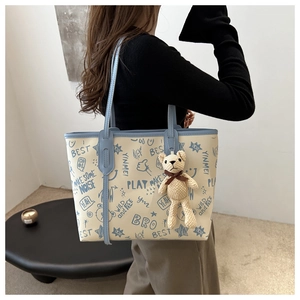 Detail of canvas tote bag with blue graffiti print and cute beige bear charm on side