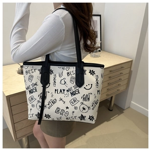 Detail of off-white tote bag featuring black graffiti print and long black PU leather straps