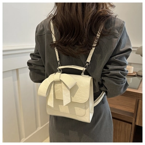 Mannequin portant un sac à dos carré crème avec un grand nœud et cuir texturé fin
