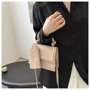 Detail of beige crossbody bag with knotted handle and matching coin purse accessory