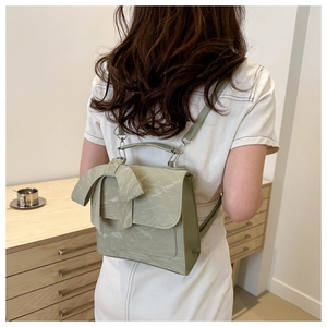 Détail d'un sac à dos vert sauge avec texture plissée et grand nœud décoratif au dos