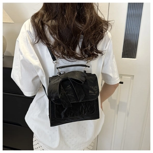 Gros plan du sac bandoulière noir plissé avec grand nœud et détail de lanière