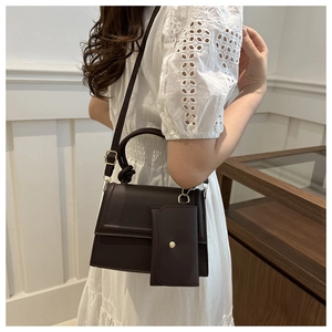 Detail of dark brown rectangle crossbody bag with twist handle and matching card pouch
