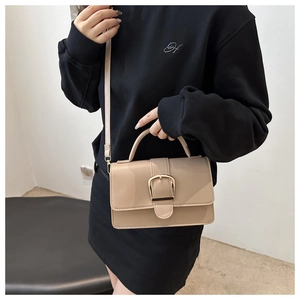 Détail du sac bandoulière vintage marron clair avec grande boucle dorée sur noir