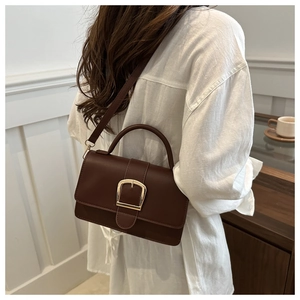 Détail du sac bandoulière marron foncé avec boucle dorée et bandoulière de luxe