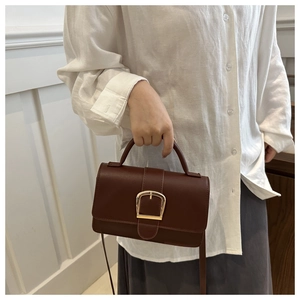 Détail du sac à main en cuir marron café avec boucle en D dorée et bandoulière réglable