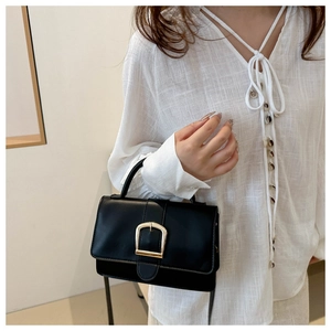 Vue détaillée du sac bandoulière noir avec boucle dorée et texture raffinée