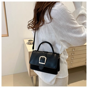 Sac à bandoulière noir élégant avec boucle fer à cheval dorée porté par un mannequin