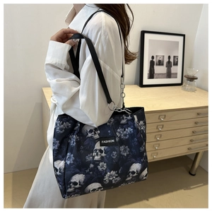 Dunkle Stofftasche mit Totenkopf und Blumenmuster an einem Model in weißer Bluse