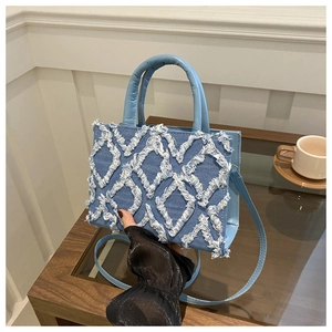 Detail of light blue denim tote with quilted raw edge patterns and stylish top handles