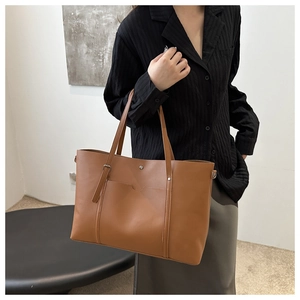 Detail of a large brown PU leather tote bag with functional front pocket and slim straps