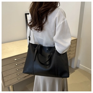 Close-up of black PU leather tote bag with metallic studs and reinforced handle details