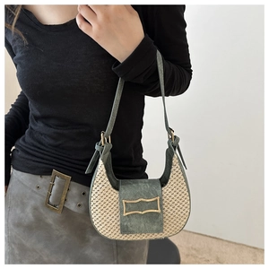 Close-up of retro crescent straw bag with dark green suede patchwork and metal buckle