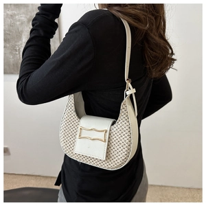 Detail of cream crescent woven bag with gold buckle on shoulder of a model in black