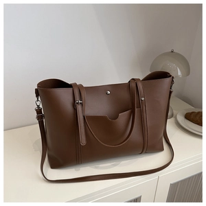 Detail of dark brown PU leather tote bag with silver metal buckle on exterior pocket